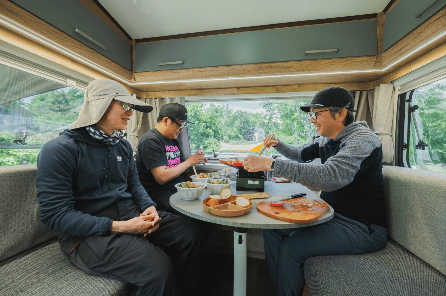トレーラーの室内で食卓を囲む3人